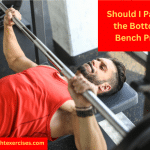 A man in a red vest performing the bench press